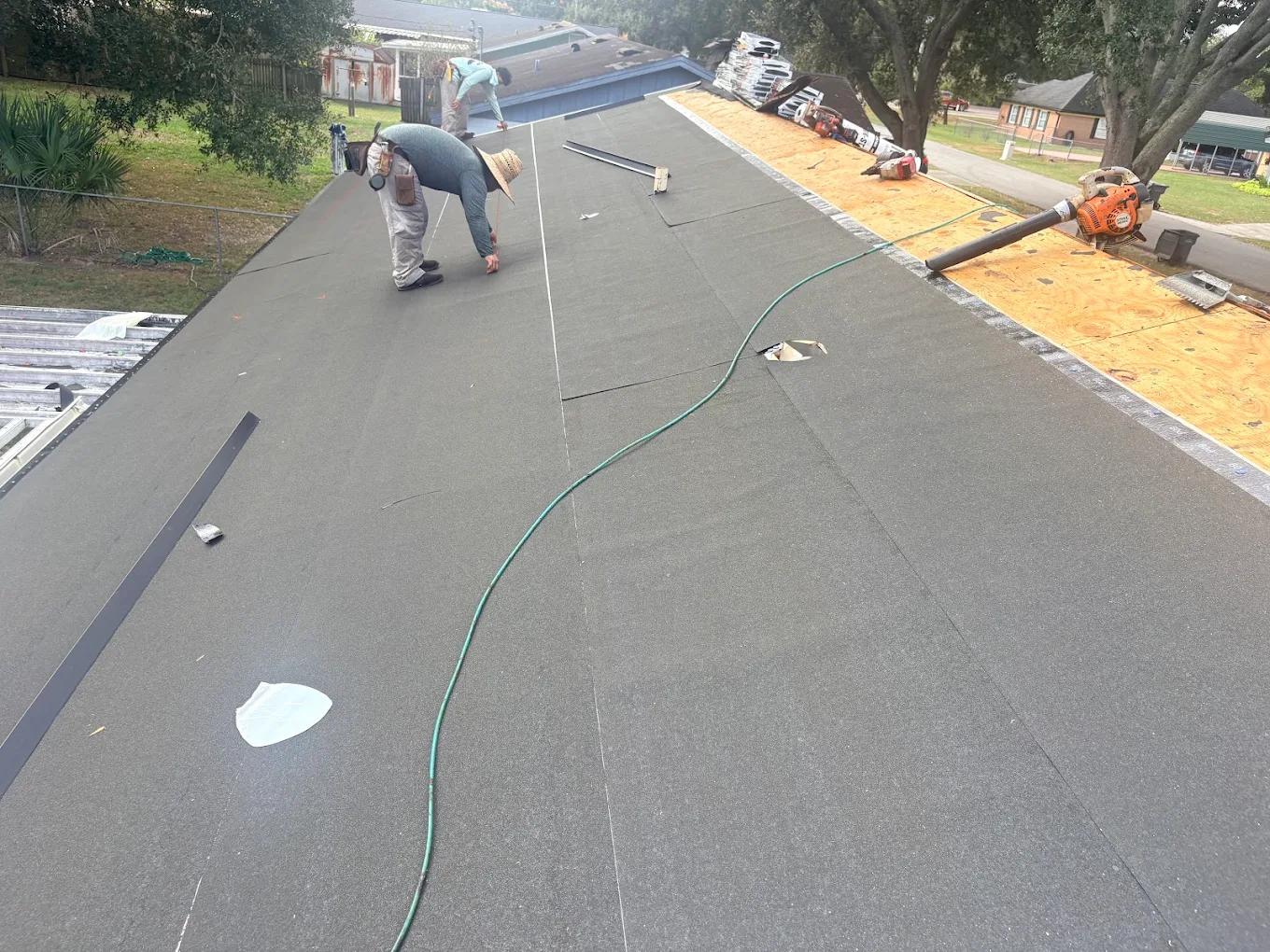 Crew installing underlayment across a residential roof.