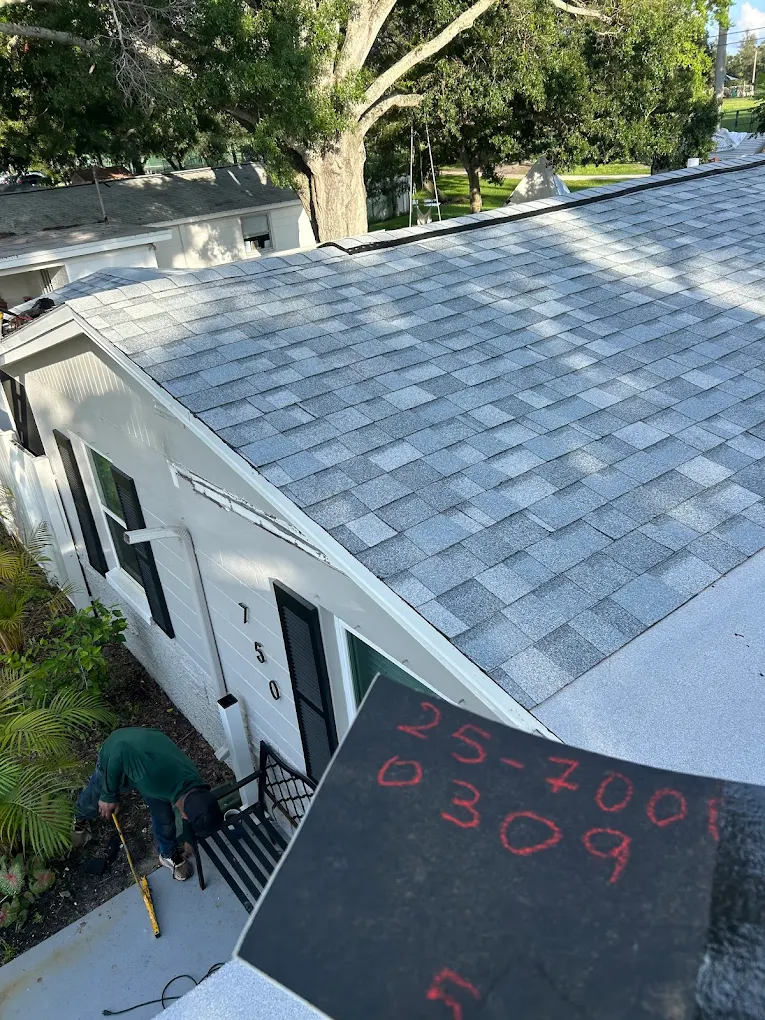 Completed gray shingle roof on a white home exterior.
